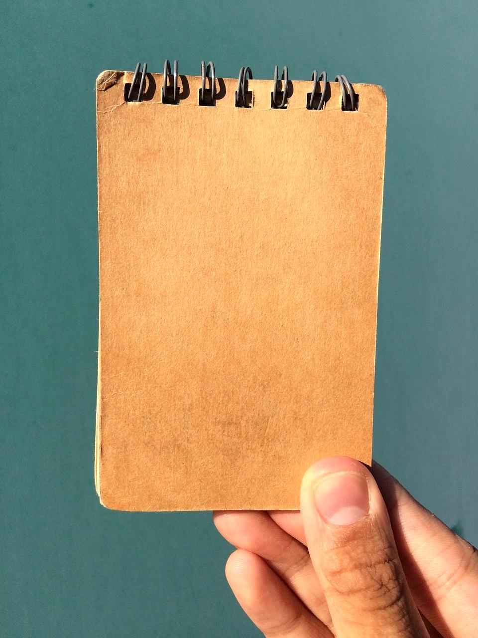 Open notebook with pens and a laptop for planning new goals